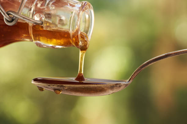 istock Pouring herbal syrup from a glass bottle onto a spoon outdoors, closeup 2178257906