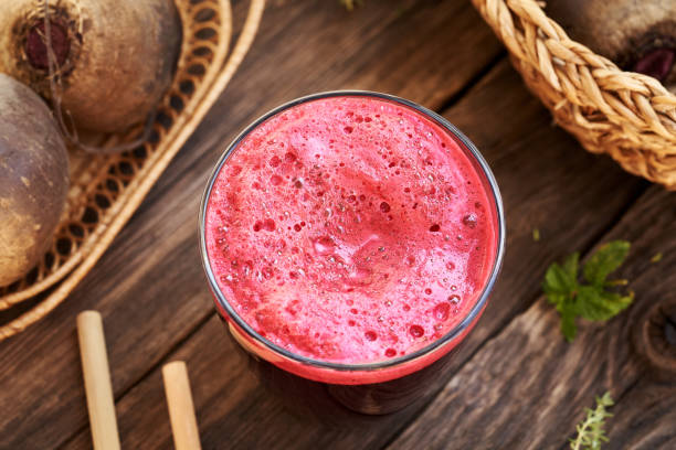 Red beet juice in a glass cup with bamboo straws on a table