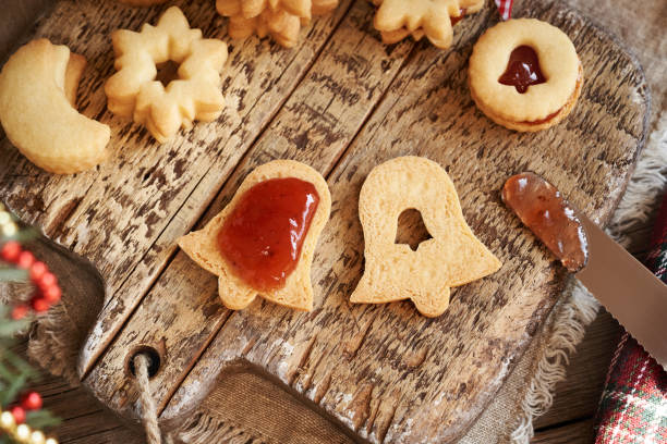 Filling homemade bell shaped Linzer Christmas cookie with strawberry marmalade, top view