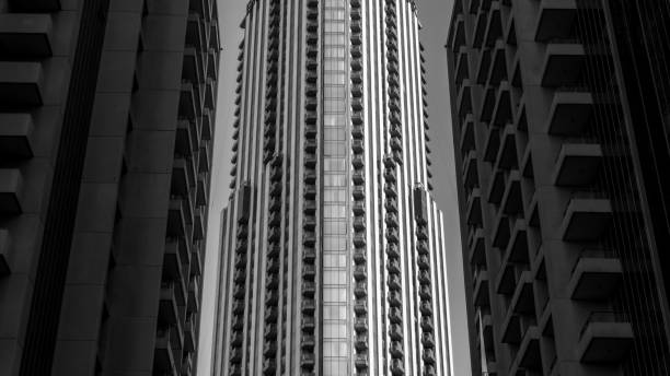 Black and white photography with a view of a detail of residential buildings in perfect alignment of a tall tower rising up between two towers on the side.