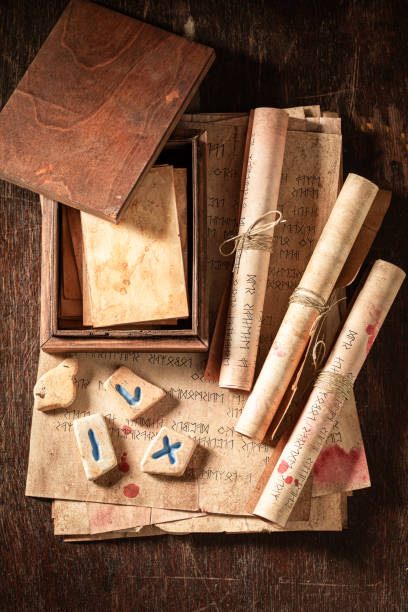 Weird divination by rune cards and stones with ancient manuscript on wooden table as a mystical background