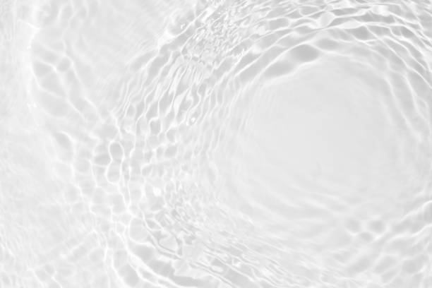 White water with ripples on the surface. Defocus blurred transparent white colored clear calm water surface texture with splashes and bubbles. Water waves with shining pattern texture background.