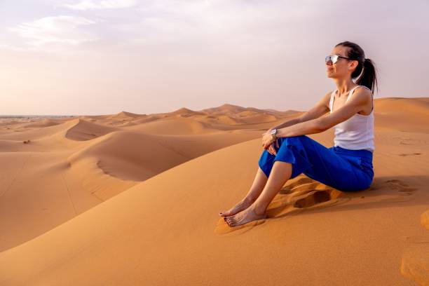 istock Woman sitting on a sand dune in a desert landscape 2178265534