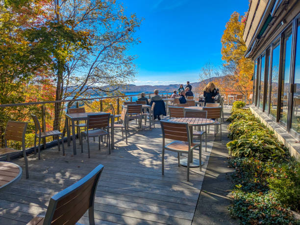 People on chairs in a cafe next to a lake in Adirondack experience museum in NY State on October 04/2024