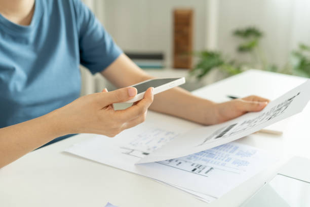 istock woman use phone to scan barcode or QR codes to pay credit card bill after receiving document invoice online. payment, receive, paying electricity, digital payments, technology, scanning, financial transactions 2178272208