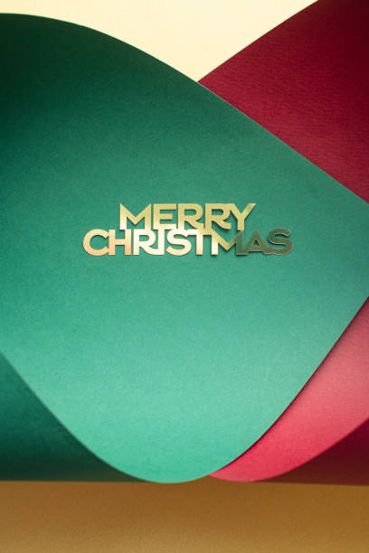 A vibrant red gift box features elegant white cursive 'Merry Christmas' lettering and small white star accents on its lid. The box is positioned amid bundles of red and white striped candy canes and strands of multicolored twinkling Christmas lights in green, blue, red, and yellow hues. The arrangement creates a warm, joyful holiday atmosphere suitable for seasonal decorations. This image is ideal for commercial uses such as Christmas greeting cards, holiday advertisements, e-commerce product promotions for gifts and decorations, social media posts for festive content, and editorial features on winter celebrations. No people are present, emphasizing the festive objects in an indoor setting during the winter season.