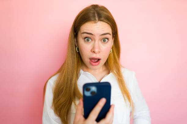 istock Surprised woman holds a smartphone, showing a shocked expression as she reads the screen 2178272423