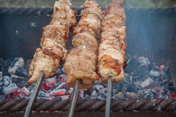Meat on skewers is fried in a charcoal grill. The concept of cooking outdoors