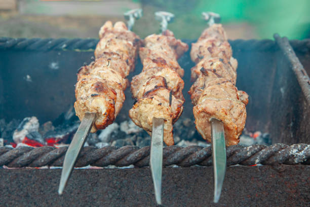 Meat on skewers is fried in a charcoal grill. The concept of cooking outdoors