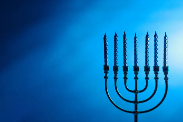 Jewish candlestick Menorah with candles on blue background, space for text. Hanukkah celebration concept.
