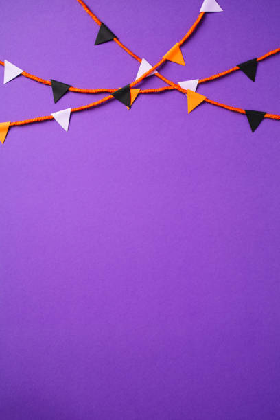 Bunting garland made of black, purple, and orange triangular flags on a purple background. Banner design for party, celebration, and festive decoration themes