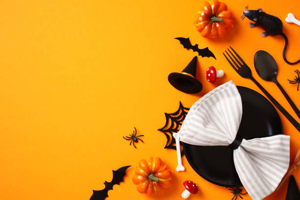 istock Halloween table setting, top view. Flat lay black plate with napkin, cutlery, scary decorations, bats, spiders, pumpkins on orange background 2178276319
