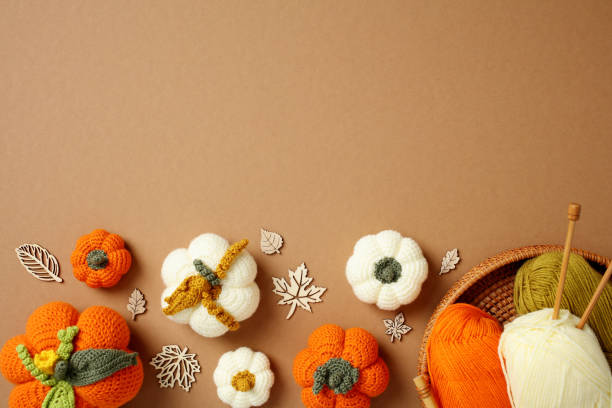 istock Flat lay handcrafted autumn decorations featuring crocheted pumpkins, yarn, and knitting needles on a warm brown background. Top view cozy home decor, and creative fall crafts. 2178276496
