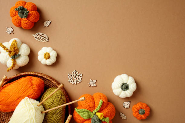istock Top view handcrafted autumn decorations featuring crocheted pumpkins, yarn, and knitting needles on a warm brown background. 2178276707