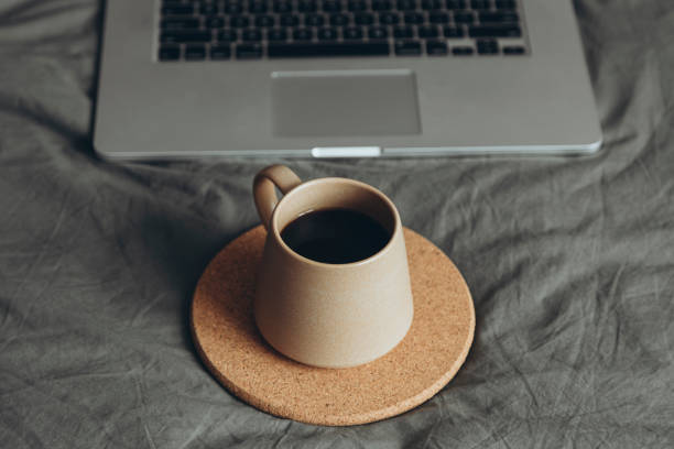 istock Ceramic cup on grey bed in bedroom and laptop on grey bedding near drink. 2178279286