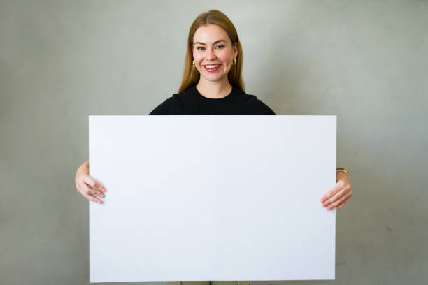 istock Happy woman displaying a blank whiteboard with ample space for your message or design 2178283354