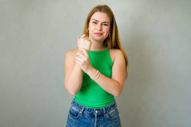 Caucasian woman holding her painful wrist, feeling a painful sensation caused by a tendonitis or a carpal tunnel syndrome