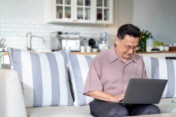 istock An elderly man sits on a couch at home, working on his laptop in a modern, comfortable setting. The scene emphasizes technology use, productivity, and independence in senior living. 2178284372