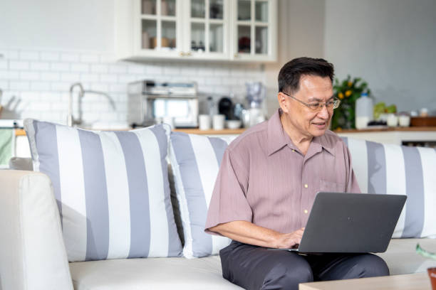 istock An elderly man sits on a couch at home, working on his laptop in a modern, comfortable setting. The scene emphasizes technology use, productivity, and independence in senior living. 2178284376