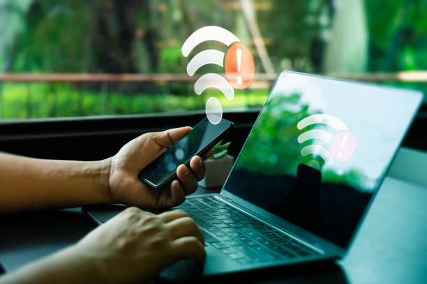 Person Holding Smartphone and Laptop with Wi-Fi Connection Error Warning in Modern Workplace. Internet Connectivity Issues Symbolized by Red Alert Icons on Devices, Unable to connect