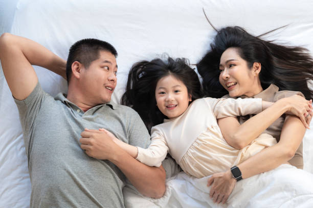 istock A joyful mother and daughter laughing together while lying on a bed. The playful moment showcases their strong bond and happiness in a comfortable home setting, surrounded by natural decor. 2178297600