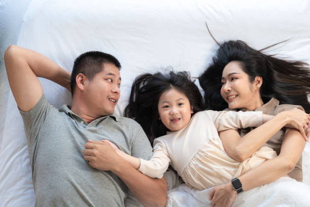 istock A joyful mother and daughter laughing together while lying on a bed. The playful moment showcases their strong bond and happiness in a comfortable home setting, surrounded by natural decor. 2178297616