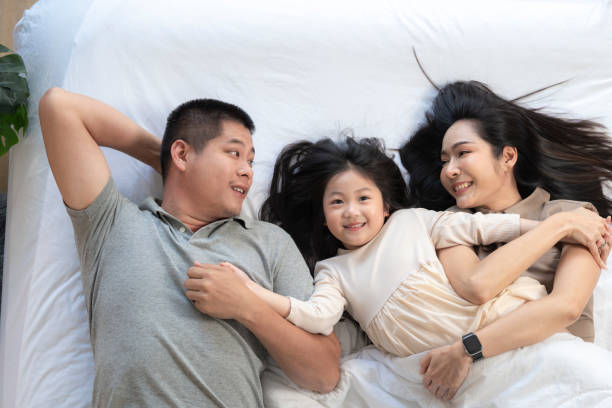 istock A joyful mother and daughter laughing together while lying on a bed. The playful moment showcases their strong bond and happiness in a comfortable home setting, surrounded by natural decor. 2178297768