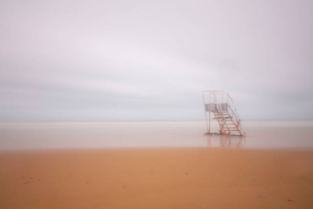 Lifeguard rescue can on the beach. Orange rescue buoy in vertical position on the sand. Horizontal composition. Copy space at right.