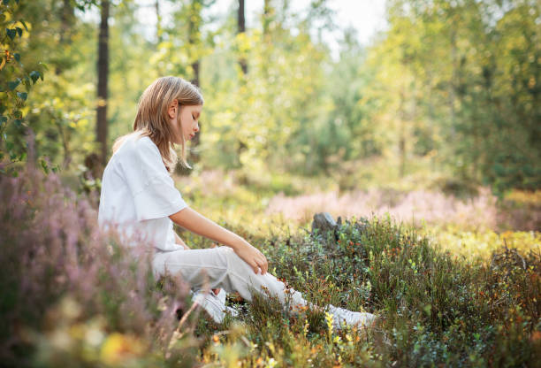 istock A young child sitting quietly in a serene forest, surrounded by vibrant greenery during a sunny afternoon 2178303178