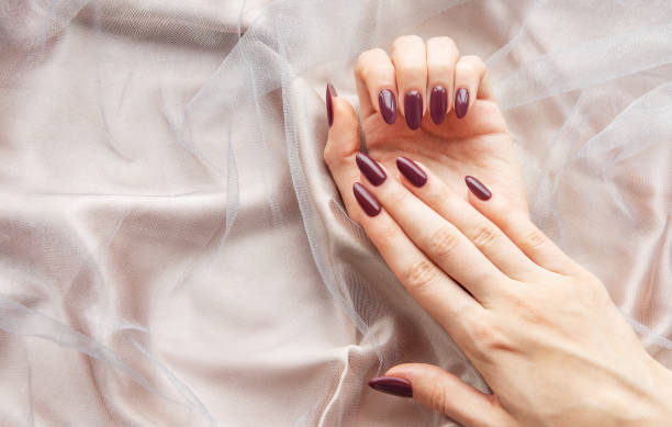 istock Elegant hands with deep burgundy nails resting on soft, sheer fabric in a calm, indoor setting during daytime 2178303941