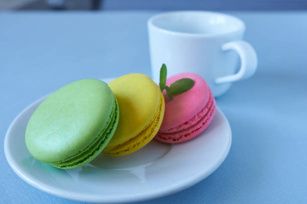 Colorful macaroons on a white plate with a cup of coffee