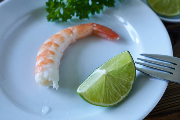 Shrimp with lime and parsley on a white plate, close-up