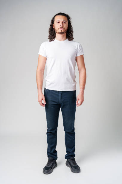A young man with curly hair stands confidently against a neutral background