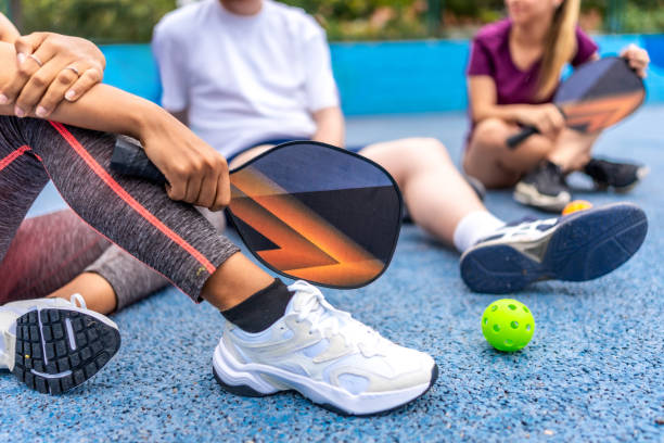 Woman holding pickelball racket while talking with friends