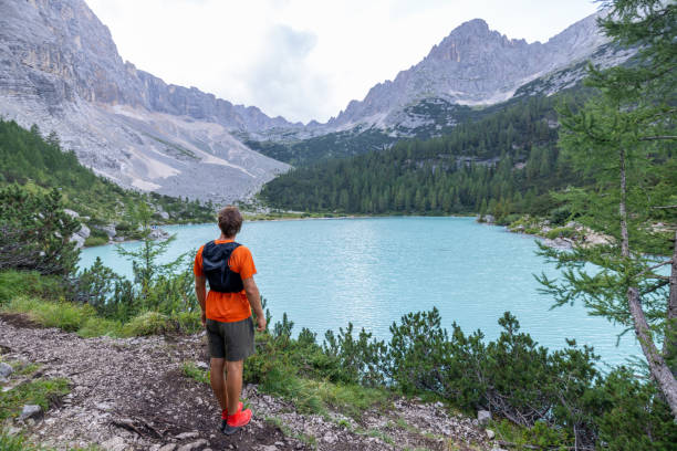 istock Man Hiking by Turquoise Mountain Lake with Rocky Peaks 2178305341