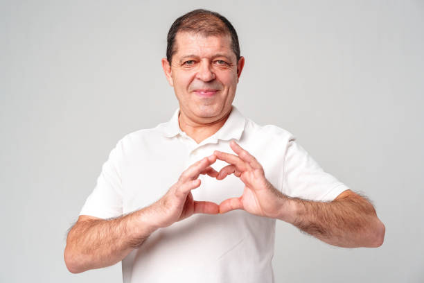 istock A smiling middle-aged man forming a heart shape with his hands against a light gray background 2178305888