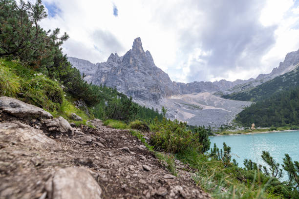 A serene mountain lake with crystal-clear turquoise waters, surrounded by rugged rocky peaks and lush green trees.