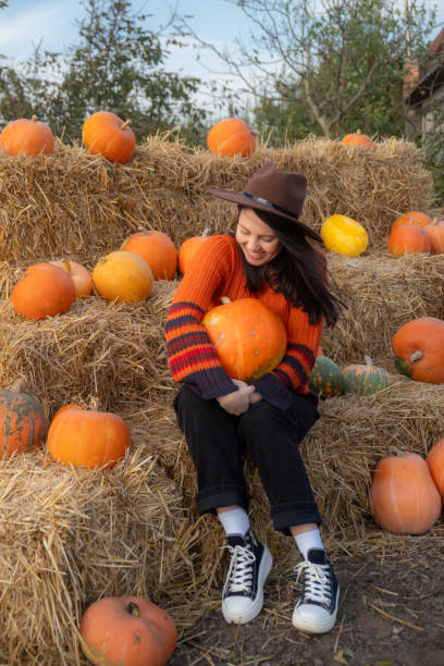 istock Woman holding a pumpkin sitting on hay bales 2178306952