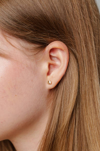 istock Close-up of a woman's ear adorned with a delicate gold stud earring in a indoor setting 2178309253