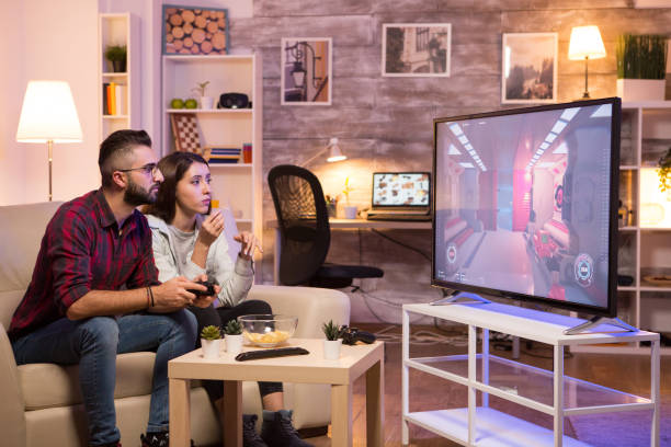 istock Man sitting on couch and playing video games on television 2178310608