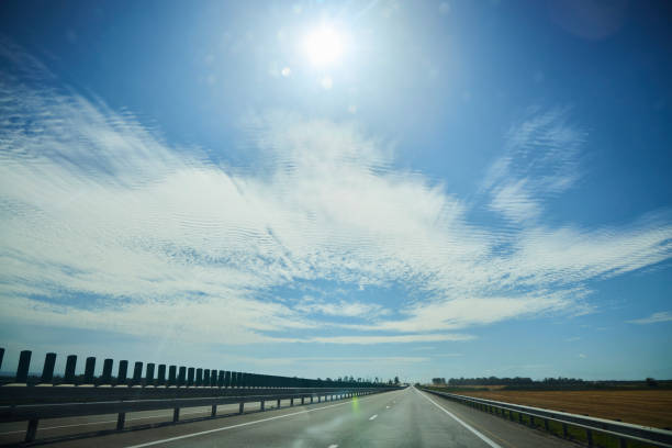 The road and the blue sky with clouds. Summer or spring, daytime.