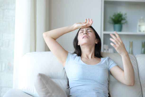 Stressed asian woman suffering heat stroke at home stock photo