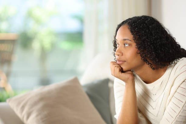 istock Black woman looking through a window in a house 2178312456