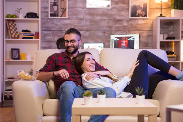 istock Cheerful young couple laughing while watching a tv show 2178312732