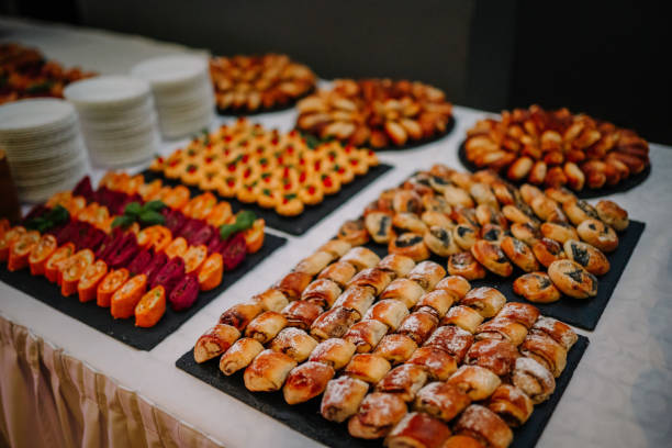 A table spread with various pastries and appetizers, including stuffed rolls, pinwheels, and savory bites, displayed on black platters, ready for a buffet.