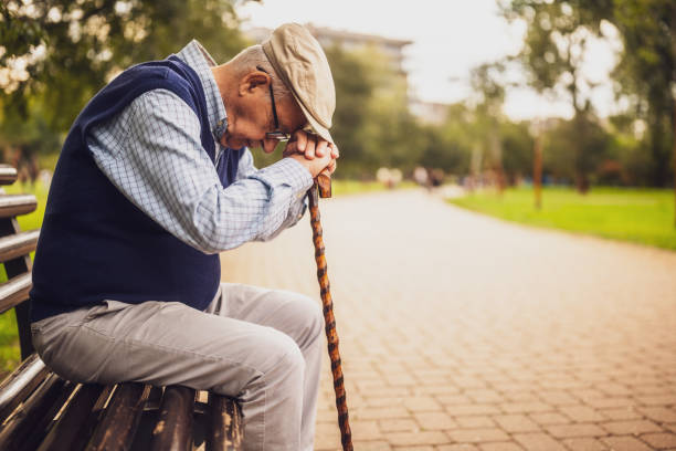 Pensive mature man sitting on a bench and thinking isolated on white background
