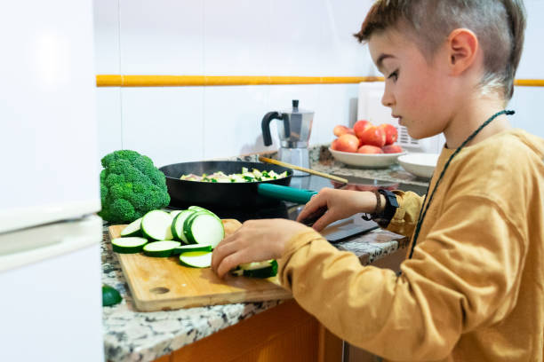 istock Boy cutting zucchini on a cutting board in the kitchen at home 2178315983