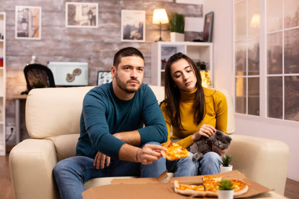 istock Gorgeous young couple eating pizza while watching TV 2178316096