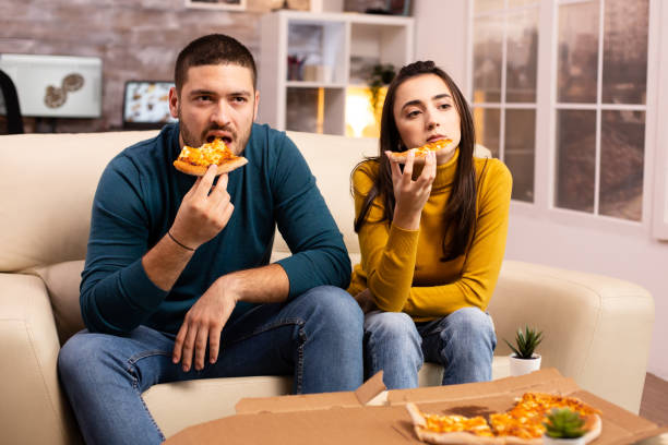 istock Gorgeous young couple eating pizza while watching TV 2178316102