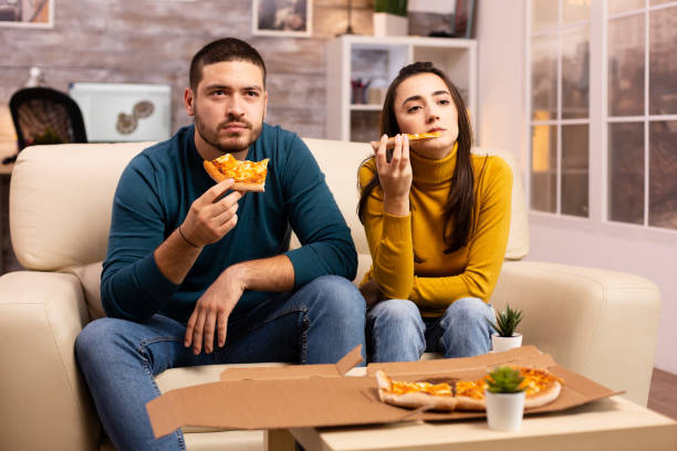 istock Gorgeous young couple eating pizza while watching TV 2178316466